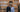 Lita and Mike Asscher standing outside the Royal Asscher Diamond Company historic building, looking thoughtfully into the distance; Lita wears a light blue suit and Mike a navy pinstripe blazer, evoking a sense of leadership and elegance.