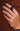 Hand wearing a Royal Asscher Oval Cut diamond ring with a halo setting, holding a navy ribbon on a brown background.