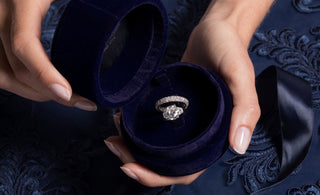 Royal Asscher Oval three stone ring with oave wedding band is placed in blue velvet Royal Asscher engagement box.