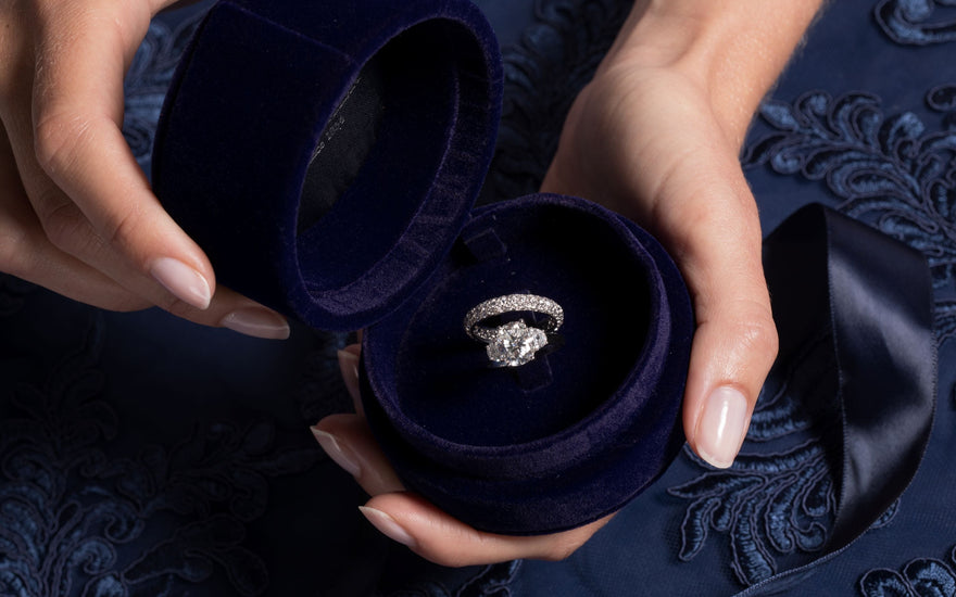 Royal Asscher Oval three stone ring with oave wedding band is placed in blue velvet Royal Asscher engagement box.
